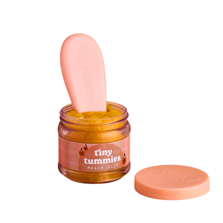 Barattolo magico Tiny Harlow Tiny Tummies con gelatina alla pesca, cucchiaio per la pappa e coperchio "gratta e annusa"; il barattolo aperto mostra del cibo finto color pesca-arancio