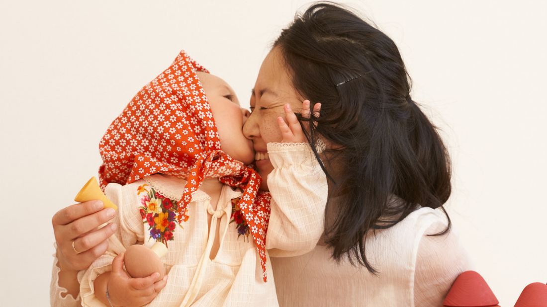 Mother and baby sharing joyful moment while playing with sustainable wooden toys - illustrating mindful parenting through educational play