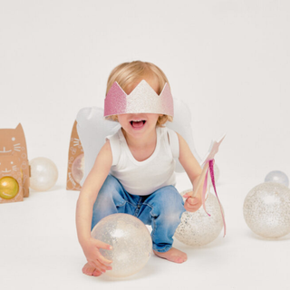 Child wearing a pink and white headband with decorative elements on a light background
